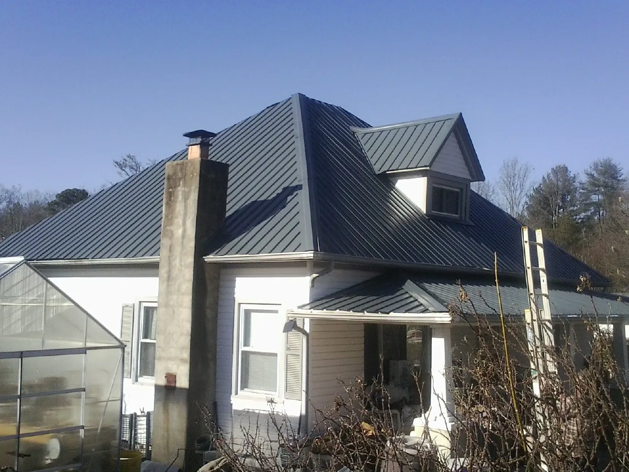 Dark blue standing seam metal roof on a white farmhouse with dormer — Slate & Tile Roof Repair by Roofing Brothers in Kennebunkport