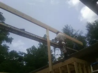 Carpenter setting a ridge beam over a new addition frame — Ice Dam Removal by Roofing Brothers in Kennebunkport