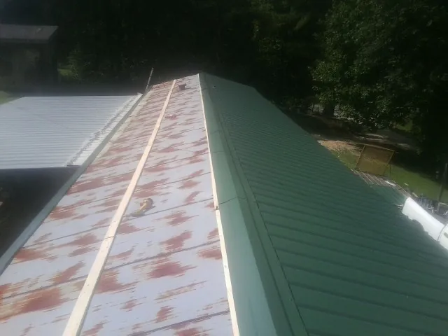 Old rusted panels beside newly installed green metal roofing — Wind Damage Roof Repair by Roofing Brothers in Kennebunkport