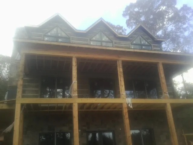 Dormers and porch framing on a large log home under construction — Roof Coating work by our crew in Kennebunkport