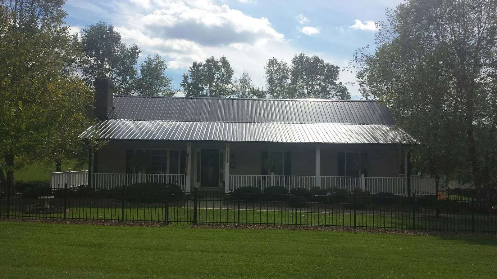 Gray metal roof on a brick ranch with a full width front porch — Gutter Guard Installation work by our crew in Kennebunkport