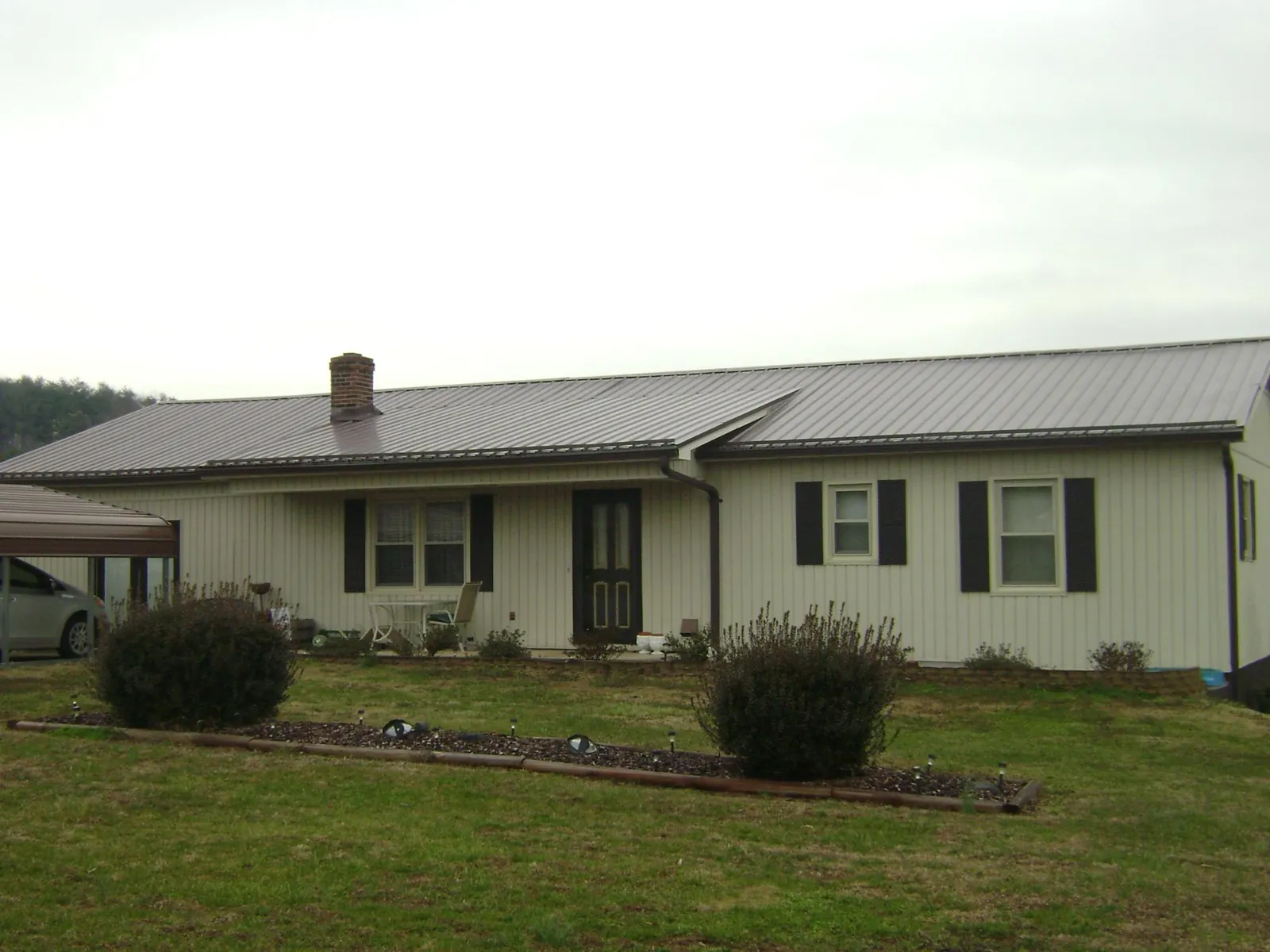 Brown metal roof on a cream sided ranch home with a brick chimney in Kennebunkport