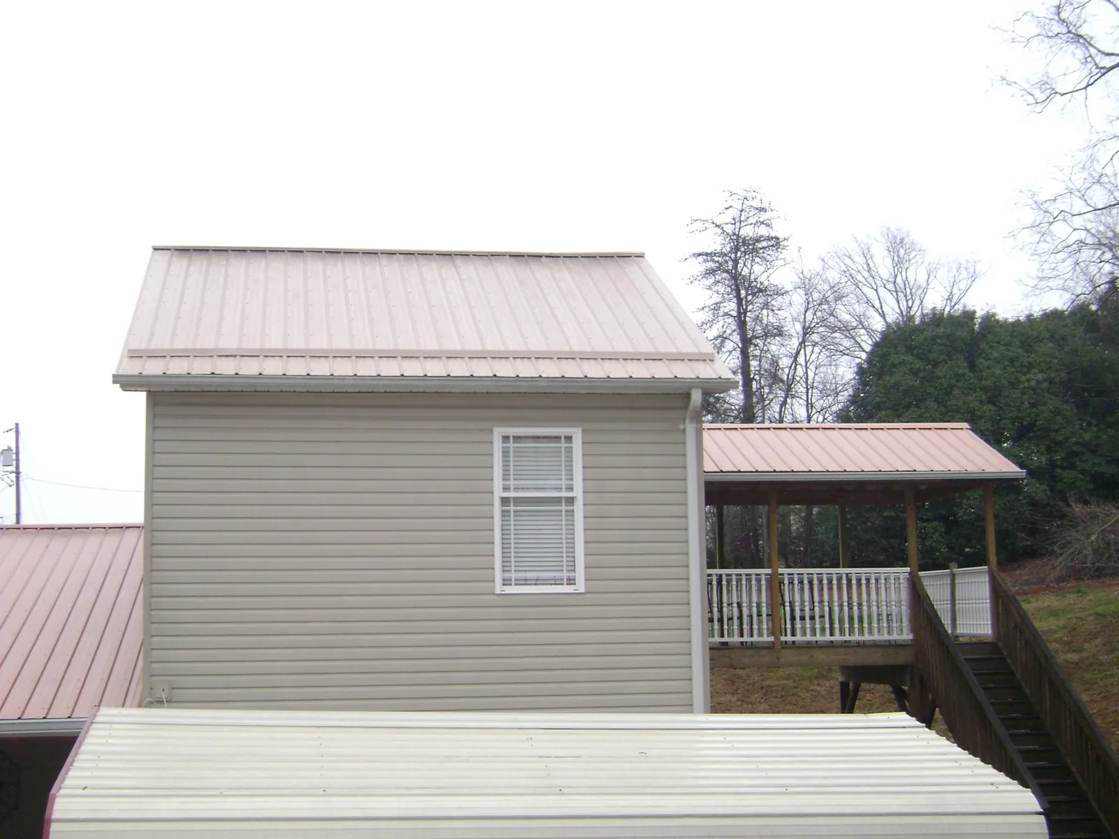 Tan metal roofs on a two story addition and attached porch, from a Roof Replacement job in Kennebunkport