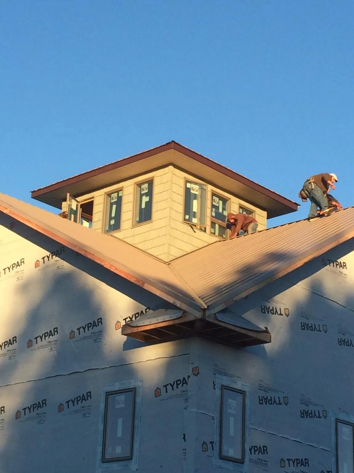 Roofers working around a rooftop cupola on a new metal roof at sunset — Roof Waterproofing in Kennebunkport by Roofing Brothers